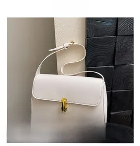 Close-up of cream-colored shoulder bag featuring a gold metal twist lock and fine stitching