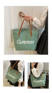 Primer plano del bolso tote de lona verde con bordado Summer y detalle de flecos suaves