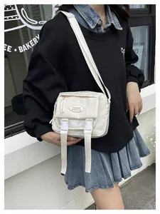 Detail of white nylon crossbody bag with dual buckles and front zipper on casual model