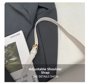 Detail view of the adjustable off-white leather shoulder strap with gold metal buckle