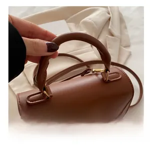 Dettaglio del manico in pelle PU marrone e della chiusura in metallo dorato di una borsa