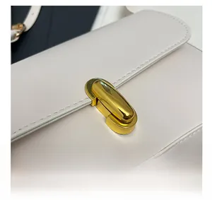 Detailed macro view of the golden metal twist lock and stitching on white leather bag