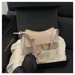 Detailed close-up of glossy beige leather saddle bag with golden oval twist-lock closure