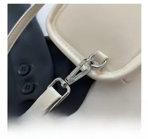 Close-up of premium silver metal buckle and strap stitching on a beige leather bag