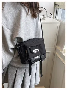 Side view of black casual crossbody bag with flap and dual buckles on a female model