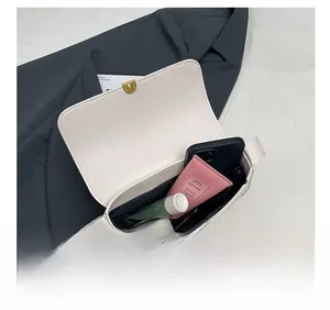 Detail showing inner storage capacity of the cream shoulder bag with metallic buckle