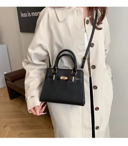 Close-up of elegant black leather tote with gold hardware shown on a model