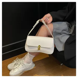 Detail of white leather shoulder bag featuring a gold matte buckle and flap closure