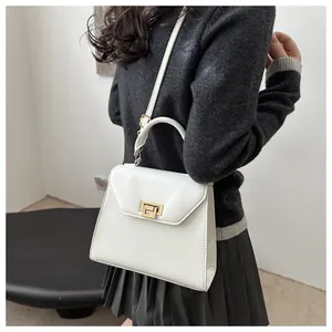 Borsa a tracolla bianca a trapezio con chiusura dorata indossata da una modella con stile