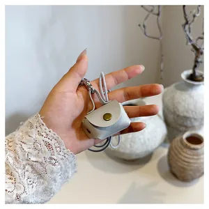 Micro-oortelefoontasje van lichtgrijs leer met bronzen metalen drukknoop en koord