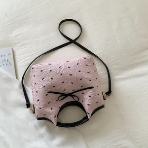 Détail du sac seau plissé rose avec imprimés de nœuds noirs et bandoulière amovible