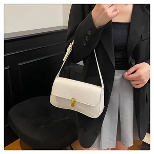 Close-up of a cream white underarm bag featuring a golden oval lock and fine leather texture