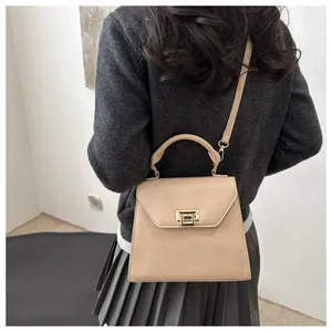 Borsa a trapezio in pelle beige con chiusura dorata vista dal retro su una modella