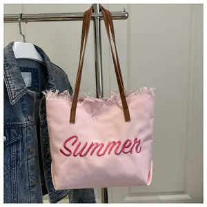 Detalle del bordado Summer en bolso tote de lona rosa con bordes de flecos rústicos