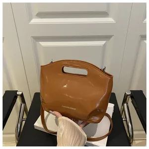 Dettaglio della borsa lucida color caramello con manico ovale e scritta in rilievo