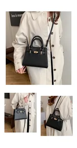 Detail of matte black leather handbag with gold twist lock and adjustable shoulder strap