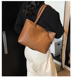 Détail de la vue arrière d'un grand sac cabas tressé marron porté par un mannequin