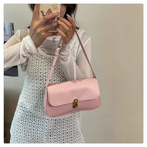 Close-up of pink underarm bag featuring a golden twist lock and adjustable shoulder strap