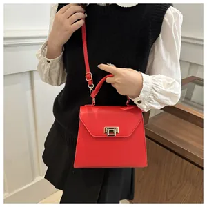 Dettaglio borsa in pelle opaca rossa con fibbia dorata e tracolla regolabile