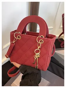 Close-up of red quilted crossbody bag with gold hardware and twin key charms