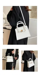 Detailed view of white minimalist handbag with gold buckle and adjustable strap