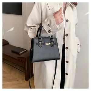 Close-up of black crossbody bag with gold hardware on model in beige trench coat