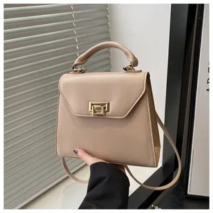 Dettaglio dell'elegante borsa beige con chiusura a rotazione dorata e finitura in pelle
