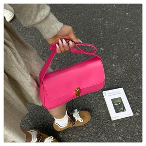 Detailed view of magenta leather shoulder bag with a polished gold metallic turn-lock