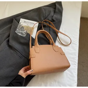 Detailed macro shot of brown lychee grain leather handbag on a grey suit background
