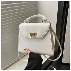 Dettaglio di una borsa a mano trapezoidale in pelle bianca con chiusura a scatto dorata