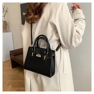 Close-up of a stylish black leather handbag with gold hardware worn with a beige trench coat