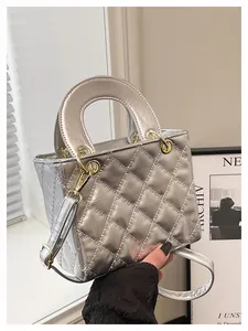 Detail of silver metallic quilted handbag featuring top handle and gold hardware
