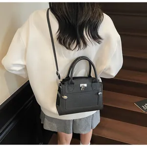 Rear view of a black lychee pattern leather crossbody bag on a model wearing it casual