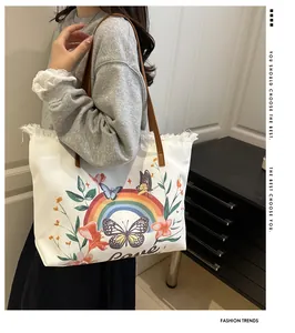 Détail du cabas en toile blanche avec broderie arc-en-ciel, bords effilés et anses en cuir
