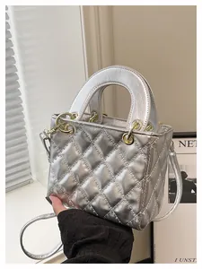 Close-up of silver quilted crossbody bag with gold hardware and top handle detail