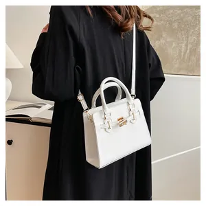 Detail of white leather handbag with golden twist lock and adjustable crossbody strap