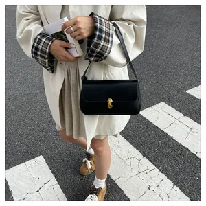 Detail of elegant black leather shoulder bag with gold metal buckle on a city street
