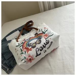 Détail d'un sac cabas en toile avec broderie florale et anses en cuir marron