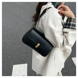 Chic black underarm bag with gold metal buckle detail shown on a white blazer outfit