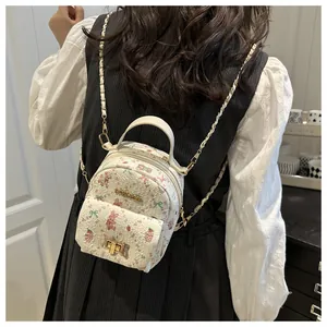 Mini cream backpack with rabbit print and metal chain strap shown on model's back