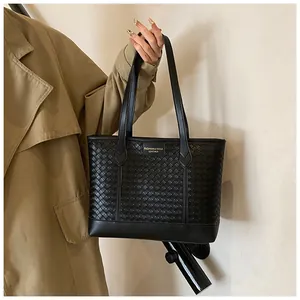 Détail du sac cabas en cuir tressé noir montrant la texture et le logo à l'épaule