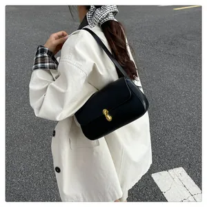 Detail of black leather underarm bag with gold twist lock on minimalist flap