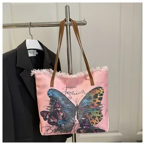 Détail du sac en toile rose avec broderie papillon, franges et lanières en cuir brun