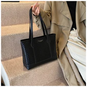 Détail du tissage en cuir noir classique et de la plaque logo sur un sac cabas