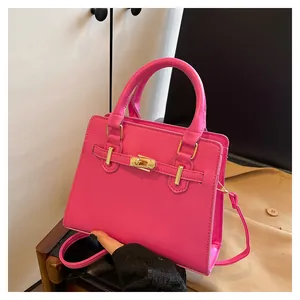 Detail of bright pink leather handbag featuring gold twist lock and adjustable shoulder strap
