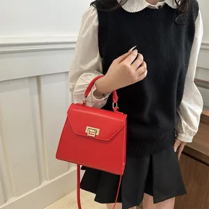 Elegante borsa a tracolla rossa in ecopelle con chiusura dorata vista su modella