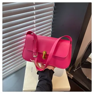 Detail shot of the magenta leather shoulder bag featuring a sleek gold twist lock closure