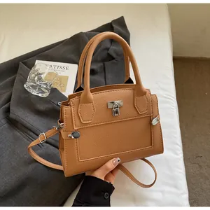 Detail of brown lychee grain leather handbag with silver lock on grey blazer fabric