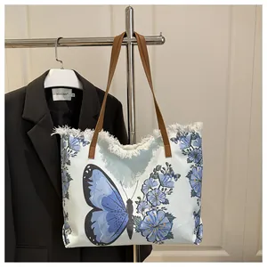Détail du sac fourre-tout en toile avec broderie papillon et franges blanches