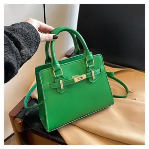 Detail of green leather handbag featuring golden metal twist lock and dual top handles